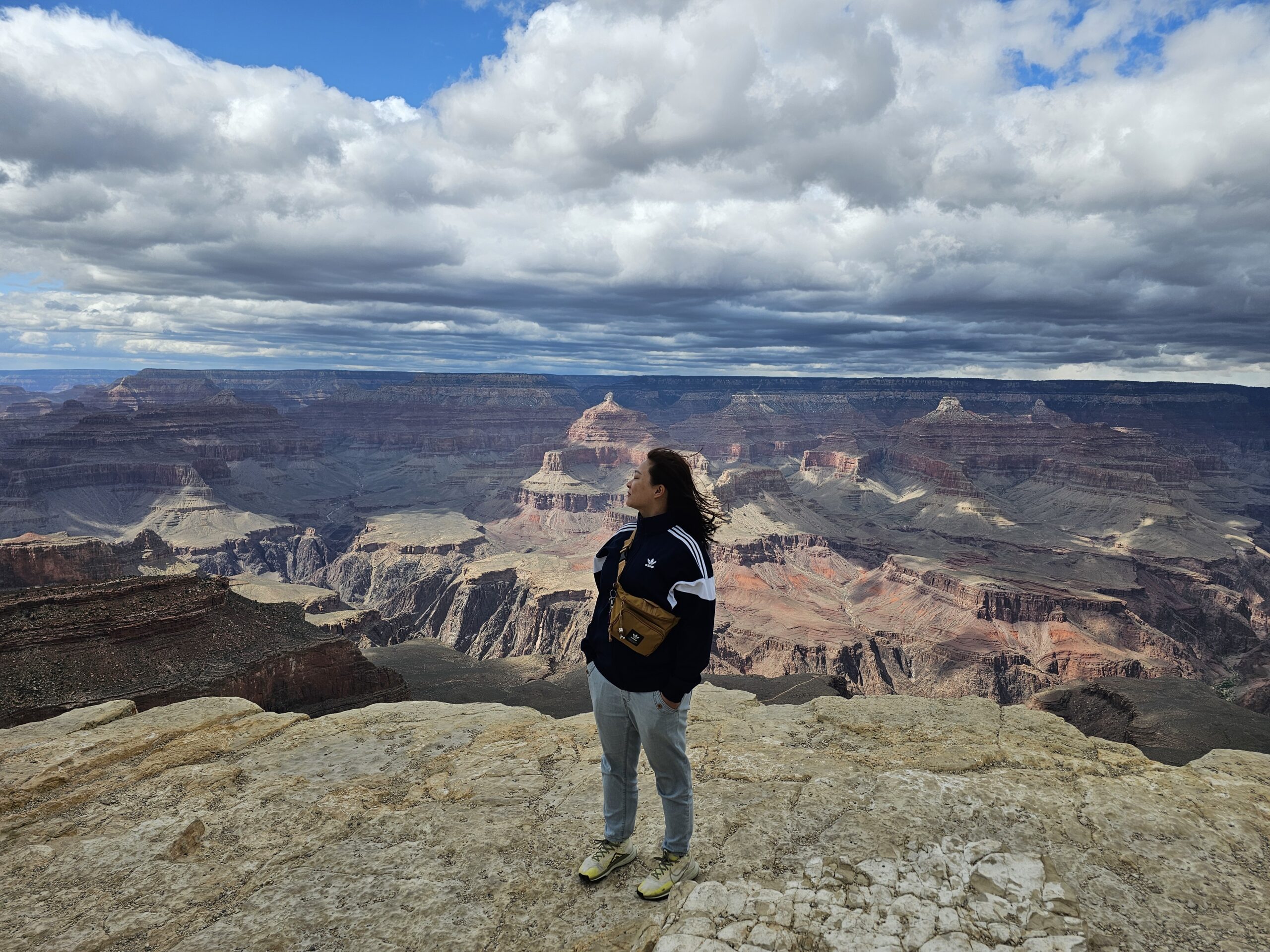 A woman standing at the edge of the Grand Canyon, embracing the vast landscape, symbolizing strength and serenity.